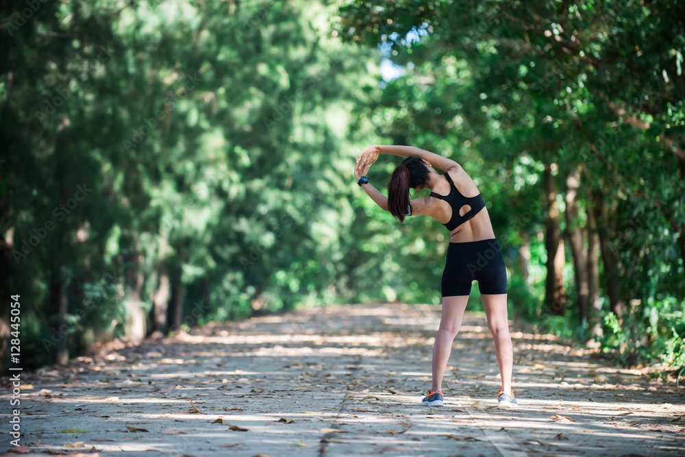 Young fitness woman stretching legs before run.