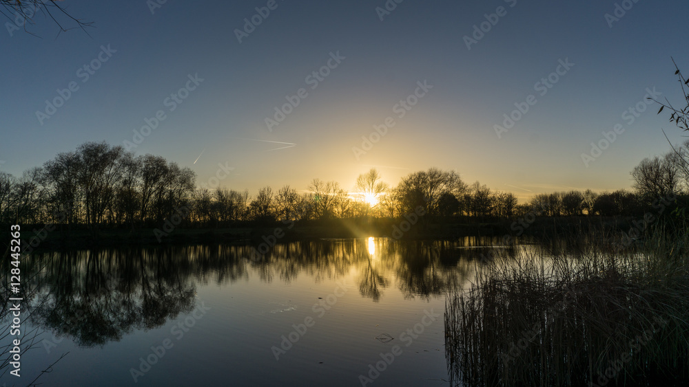 Fototapeta premium Sonnenuntergang im Herbst an einem See mi blauem Himmel