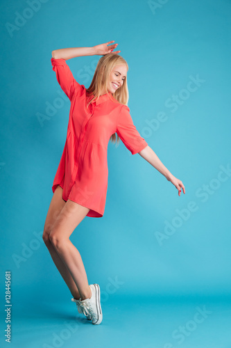 Fototapeta Naklejka Na Ścianę i Meble -  Portrait of a blonde happy woman posing on her tiptoes