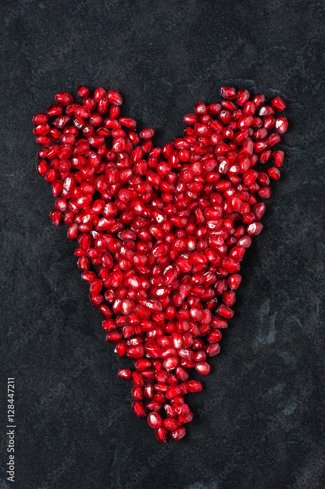 Red heart of pomegranate seeds on the black table Red heart of pomegranate seeds on the black table