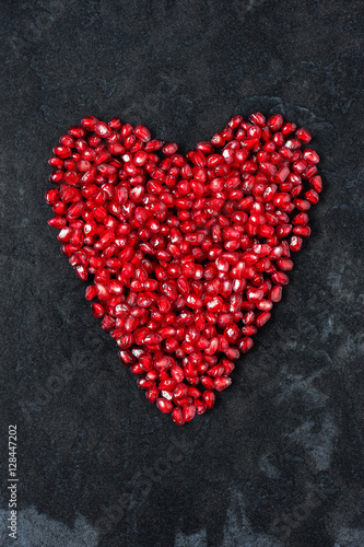 Red heart of pomegranate seeds on the black table