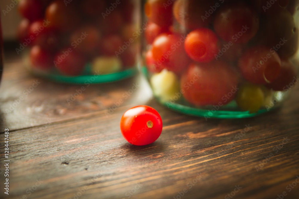 cherry tomatoes in a glass jar on a wooden background
