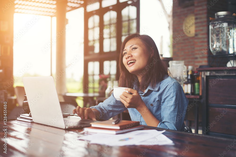 Beautiful hipster woman using laptop at cafe while drinking coff Beautiful hipster woman using laptop at cafe while drinking coff