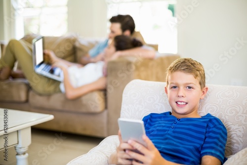 Portrait of boy sitting on sofa and using mobile phone