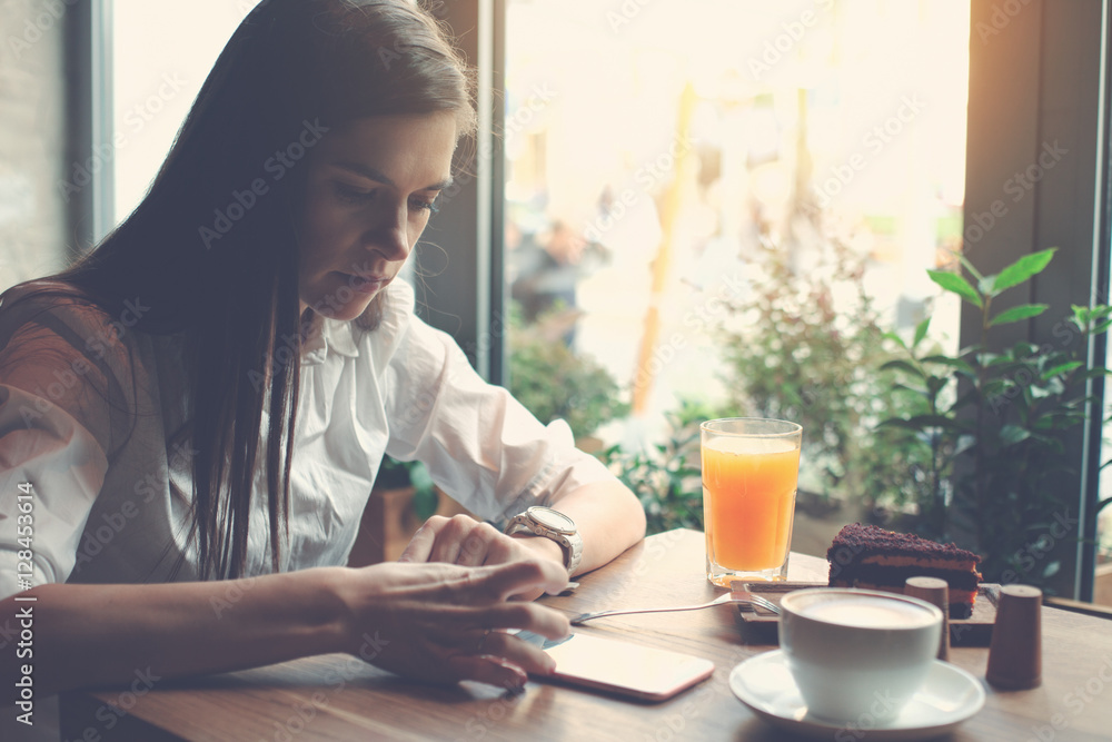 Handsome woman sitting in cafe and using mobile phone to read daily news feed Handsome woman sitting in cafe and using mobile phone to read daily news feed