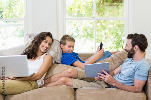 Parents and son using a laptop, tablet and phone