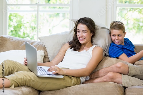 Mother and son sitting on sofa and using laptop © WavebreakMediaMicro