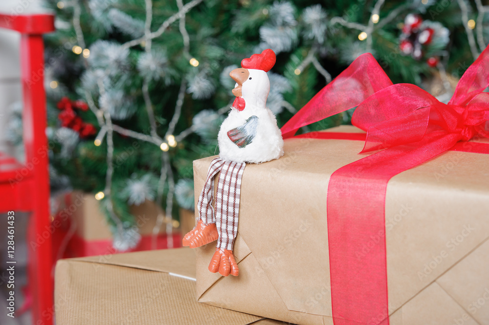 Fototapeta premium the symbol of the new 2017 rooster on the background of Christmas tree and boxes with gifts