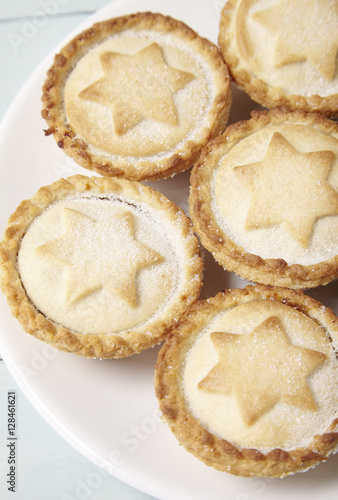 A close up of a plate full of freshly baked mince pies on a blue wooden dining table background
