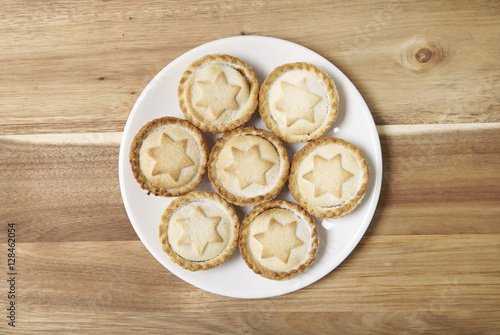 Aerial view of a plate full of freshly baked mince pies on a wooden kitchen counter background
