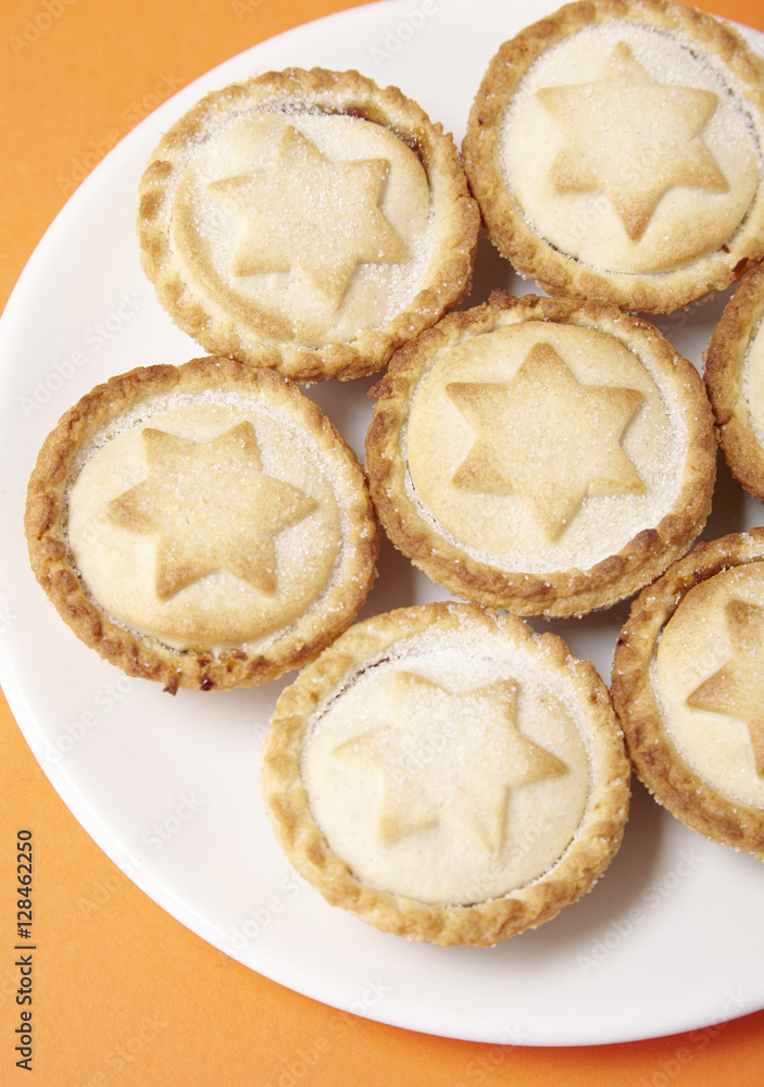 A close up of a plate full of freshly baked fruit pies on a bright orange background A close up of a plate full of freshly baked fruit pies on a bright orange background