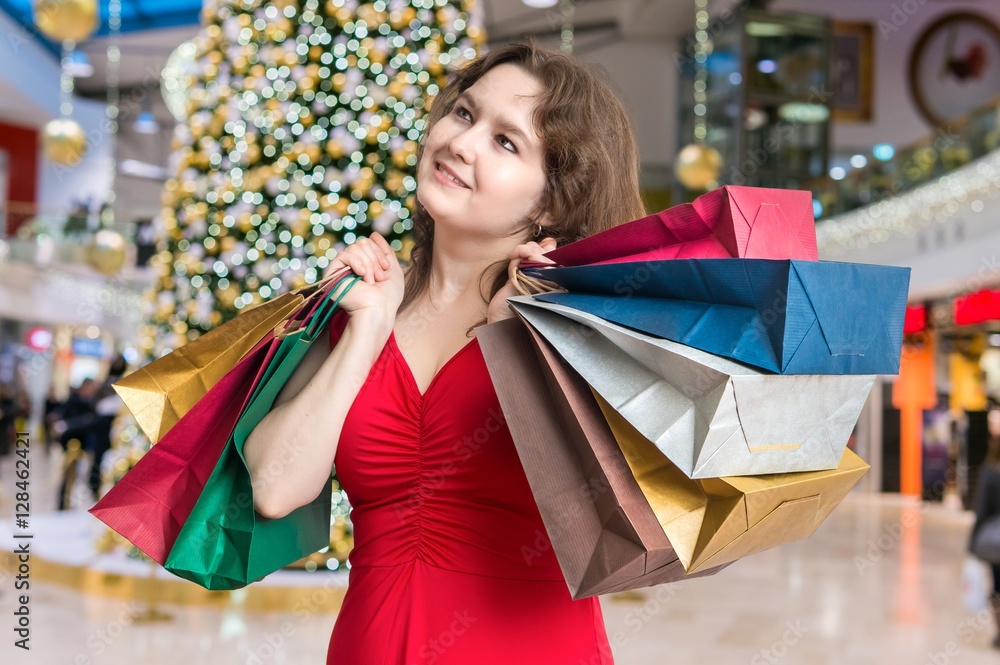 Young woman is shopping gifts for Christmas and holds many colorful shopping bags. Young woman is shopping gifts for Christmas and holds many colorful shopping bags.