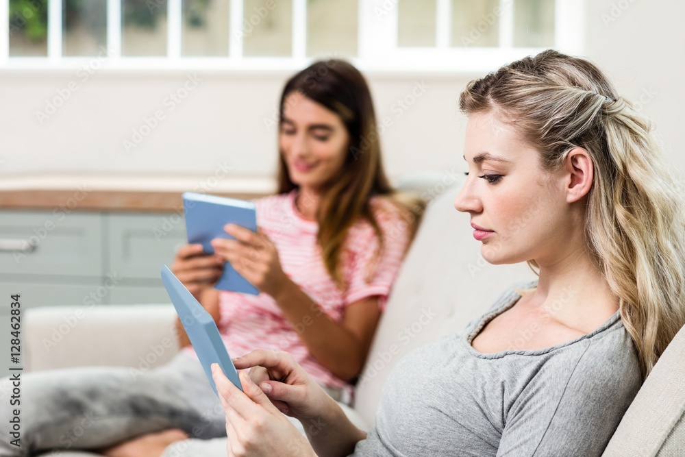 Female friends using digital tablet at home Female friends using digital tablet at home