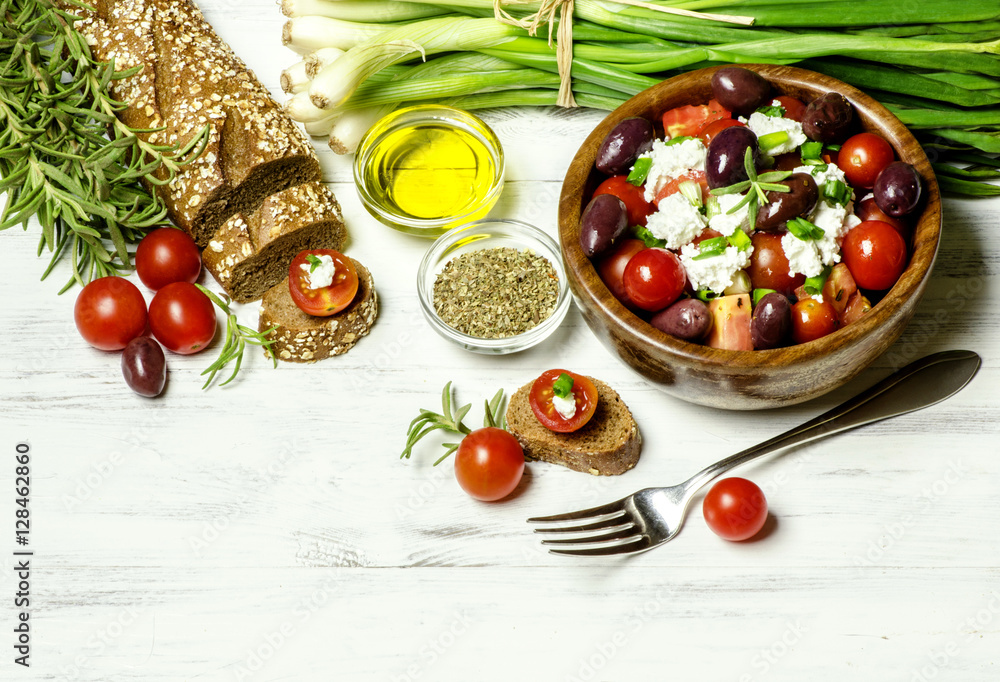 Φωτογραφία Delicious tomato salad with feta cheese,fresh green onion,wholegrain bread,olive oil,black olives and herbs on white wooden background