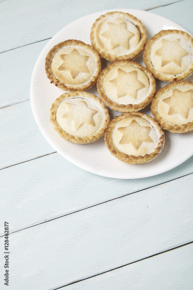 A plate full of freshly baked mince pies on a wooden table top background with blank space below A plate full of freshly baked mince pies on a wooden table top background with blank space below