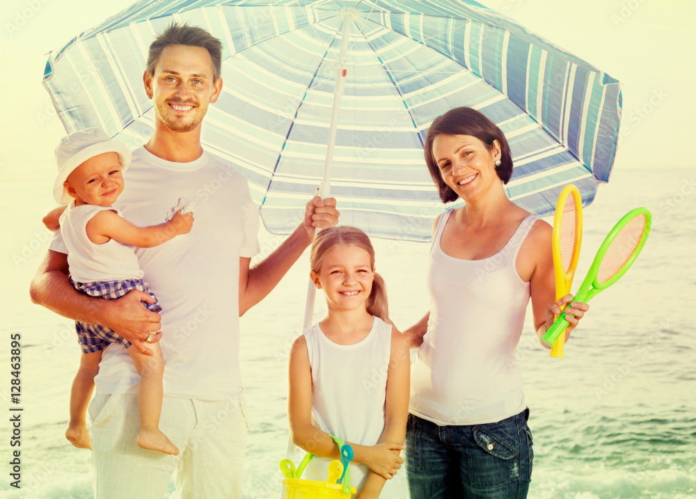 family  standing  under sun umbrella
