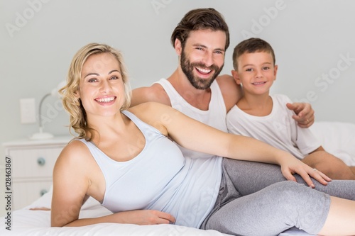 Portrait of parents and son sitting on bed in bedroom
