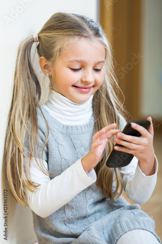 Little girl with cell phone indoors.