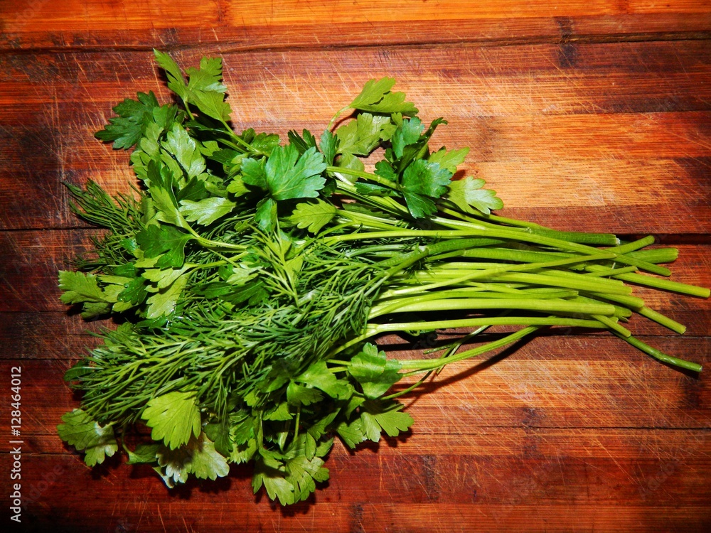 on a wooden chopping board put a big bunch of fresh herbs. Long beautiful stems of dill and fresh green stems and leaves of parsley. on a wooden chopping board put a big bunch of fresh herbs. Long beautiful stems of dill and fresh green stems and leaves of parsley.