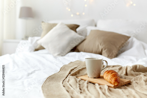 Fényképezés coffee cup and croissant on plaid in bed at home
