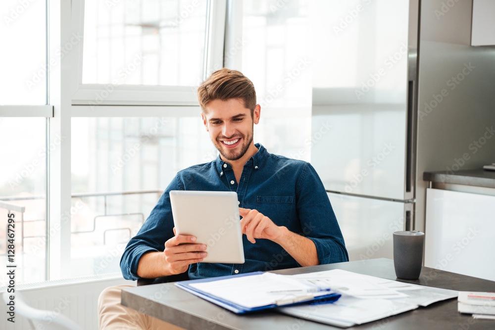 Man looking at tablet and sitting near table with documents Man looking at tablet and sitting near table with documents