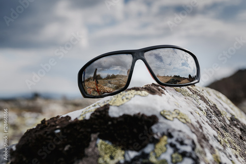 sunglasses on a stone in mountains, travel concept