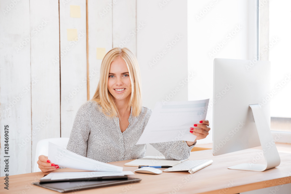Business woman working with papers and computerr in office