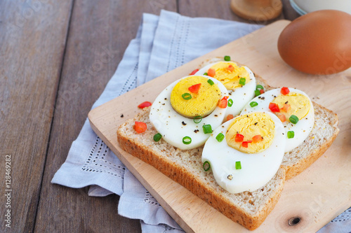 Top view of sliced boiled egg with garnish on wholemeal bread.