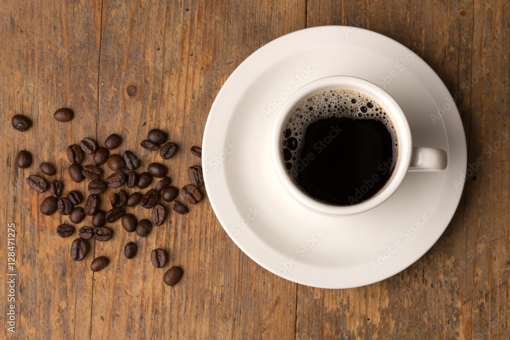 coffee cup on wooden surface with some beans close-up topview coffee cup on wooden surface with some beans close-up topview