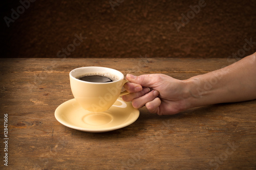 hand picks up a coffee cup from its saucer