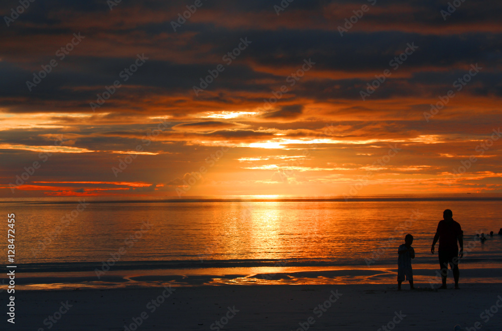 father and son enjoying sunset at beach