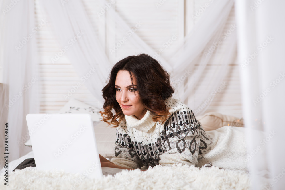 Young beautiful woman lying on the bed with laptop
Young beautiful woman lying on the bed with laptop