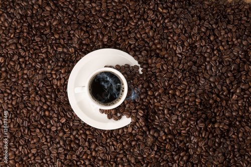 hot coffee cup on bed of roasted beans, topview