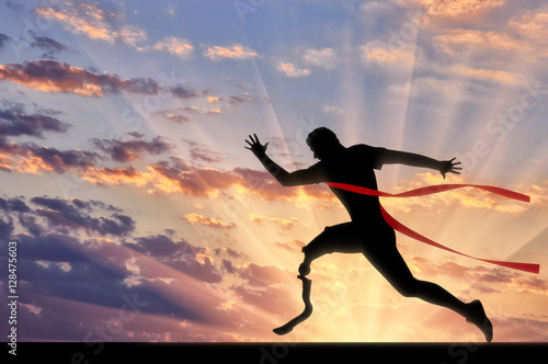 Fotografie Disabled paralympic runner with prosthetic crossing finish line sunset
