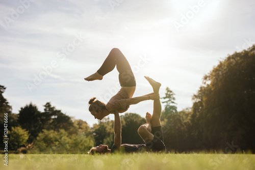 Healthy young couple doing acro yoga outdoors photo
