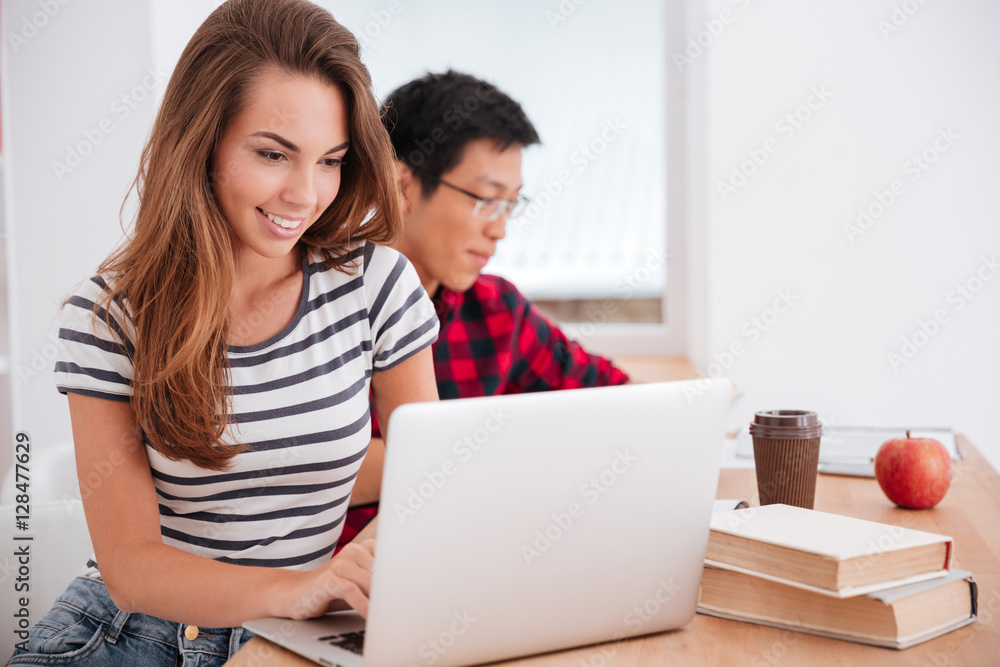 Beautiful young lady sitting in classroom and working on laptop Beautiful young lady sitting in classroom and working on laptop