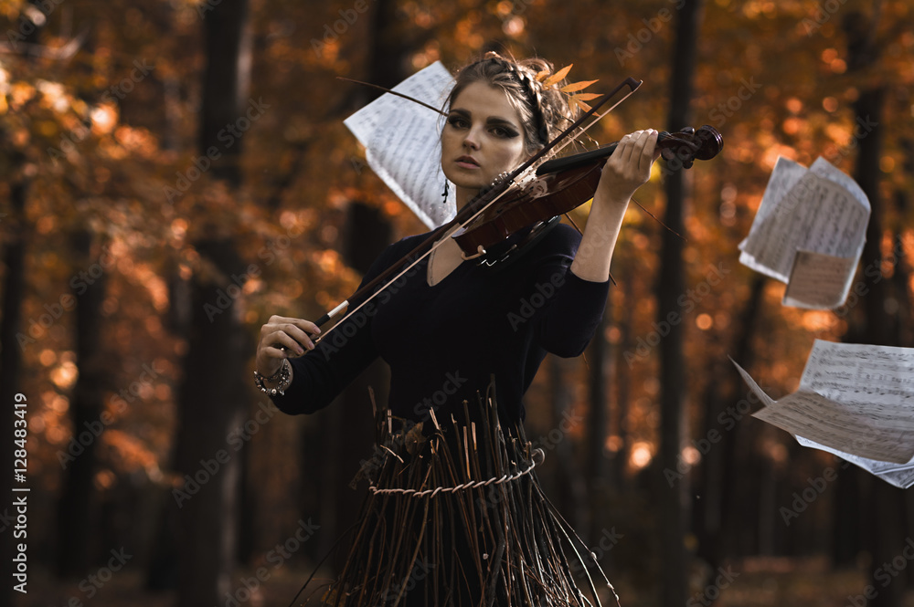 Obraz premium Young woman plays violin over the music notes flying away and fall park background