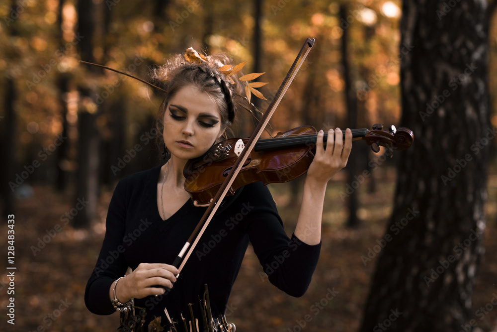 Fototapeta premium Young woman fiddle violin over the fall park background