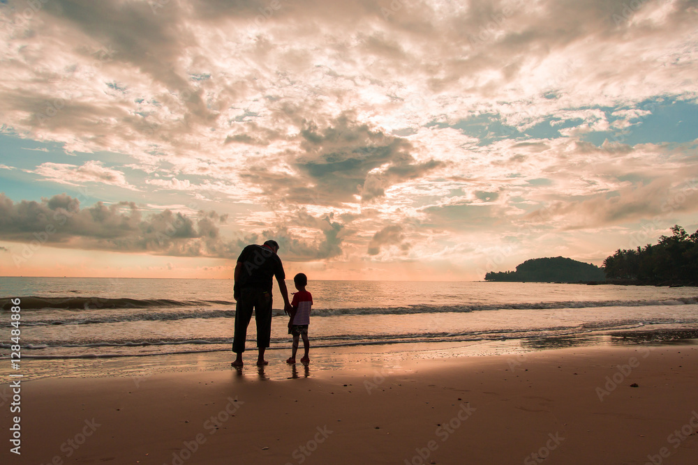 Happy family cute little boy ans dad play on beach sunrise backg