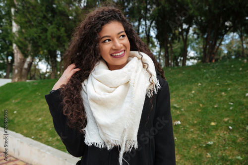 Beautiful african lady wearing scarf touching hair and look aside photo