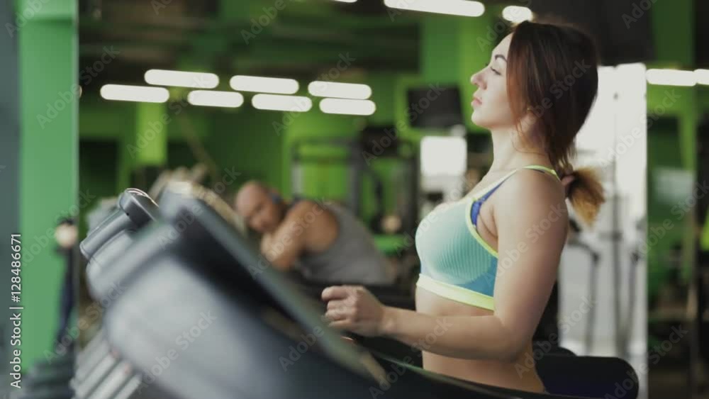 Woman in fitness center running on a treadmill Woman in fitness center running on a treadmill