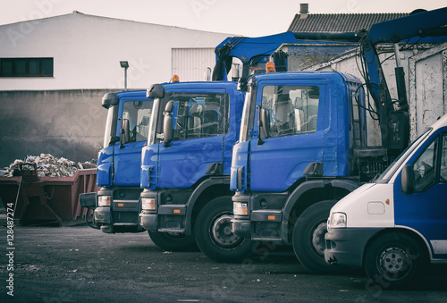 Few garbage trucks on the parking lot.