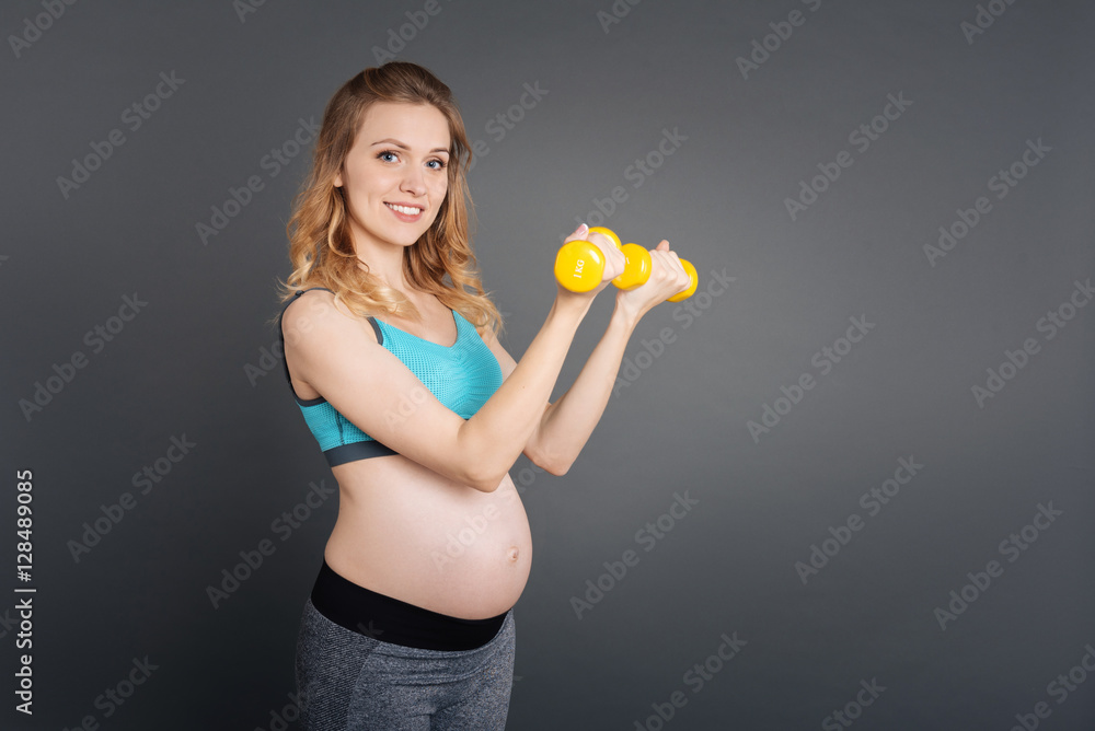 Pretty sportswoman raising the dumbbells in the bent hands Pretty sportswoman raising the dumbbells in the bent hands