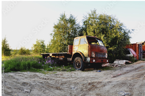 Orange old lorry stay at the tree. Summer