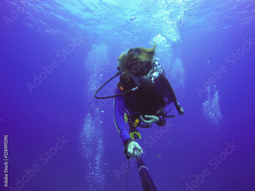 Underwater scuba diving selfie shot with selfie stick. Deep blue sea. Wide angle shot.