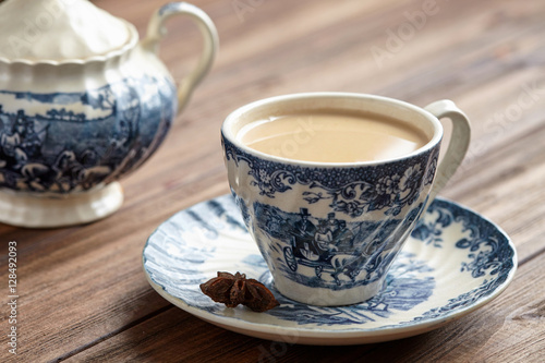 Masala tea chai latte homemade traditional Indian sweet milk with spices beverage in porcelain cup on wooden table background