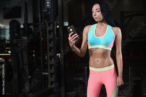 Fit woman in gym holding smart phone