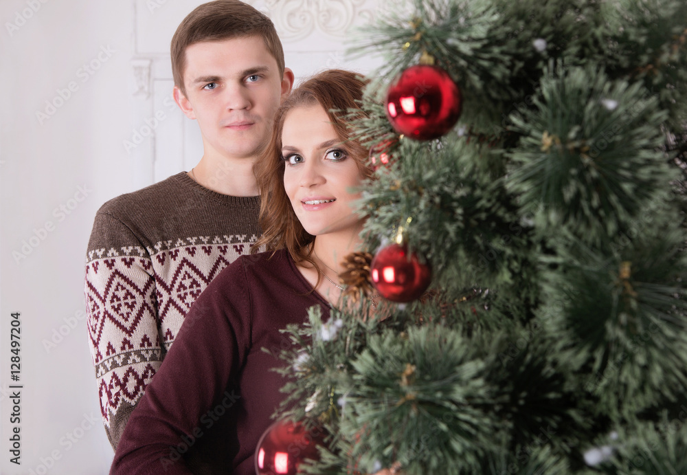 Young happy couple embracing near the Christmas tree celebrating Young happy couple embracing near the Christmas tree celebrating