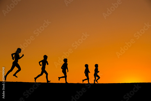 silhouette of five running kids against sunset