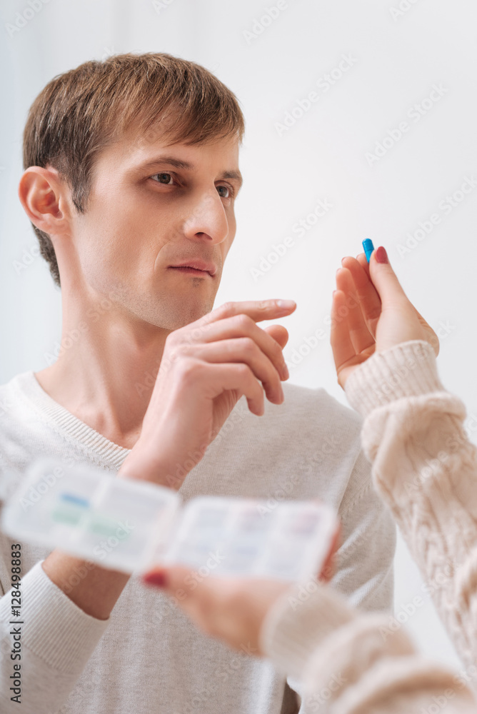 Unhappy young man taking a pill Unhappy young man taking a pill